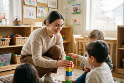 Jeune femme nounou aidant des enfants à construire une tour de blocs